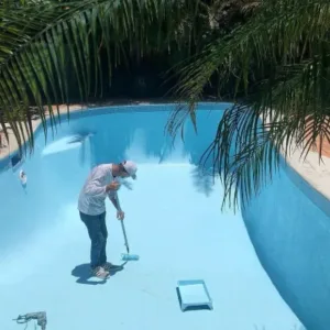 Čovek farba prazan bazen bojom za bazene